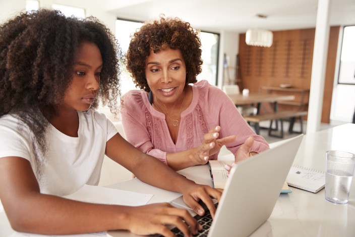 middle aged black woman helping her teenage daughter with homework, close up